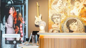Un mostrador de recepción de hotel con un espejo, una guitarra y un adorno de pared.