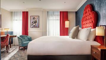 Habitación de hotel con una cama grande, un escritorio, una silla y un cuadro en la pared.