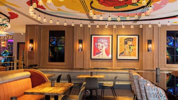 A restaurant with wooden paneling, artwork on the walls, and a variety of seating options including booths and tables.