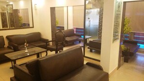 Eine Hotelhalle mit Sofas, Tischen und einer Glastrennwand.