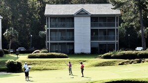 A golf course with a building in the background. - Pawleys Island Condo with Golf Views  Minutes to beach Pool/Hot Tub Dog-friendly (Pawleys Island)