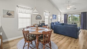 A dining area with a round table, chairs, and a ceiling fan. - Pawleys Island Condo with Golf Views  Minutes to beach Pool/Hot Tub Dog-friendly (Pawleys Island)