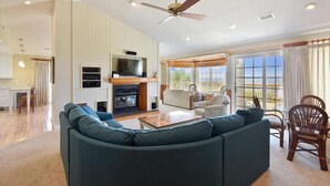 A spacious living room with a large sofa, a television, and a fireplace. - The Tayer-Soundfront at Ships Watch in Duck (Duck)