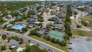 An aerial view of a residential area with houses, roads, and a tennis court. - The Tayer-Soundfront at Ships Watch in Duck (Duck)