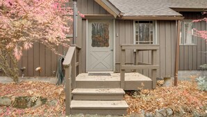 A wooden house with a gray door, a small porch, and steps leading to the entrance. - Community Perks: Retreat w/ Thirteenth Lake Access (North River)