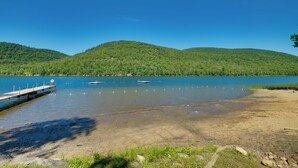 A lake with a wooden dock extending into the water, surrounded by green hills. - Community Perks: Retreat w/ Thirteenth Lake Access (North River)