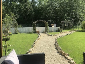 Stroll through the serene outdoor space, surrounded by lush greenery and a wooden fence, leading to a charming entrance.