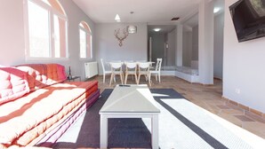 A modern living room with a sofa, a coffee table, and a dining area with chairs and a table.