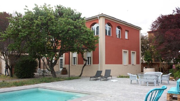 A building with a swimming pool, outdoor seating, and a garden.