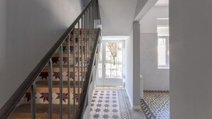 A staircase with a metal railing and patterned floor tiles leading to a door with a window.
