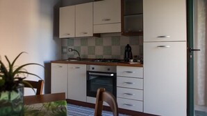 Una cocina compacta con armarios blancos, una estufa a gas y un horno empotrado.