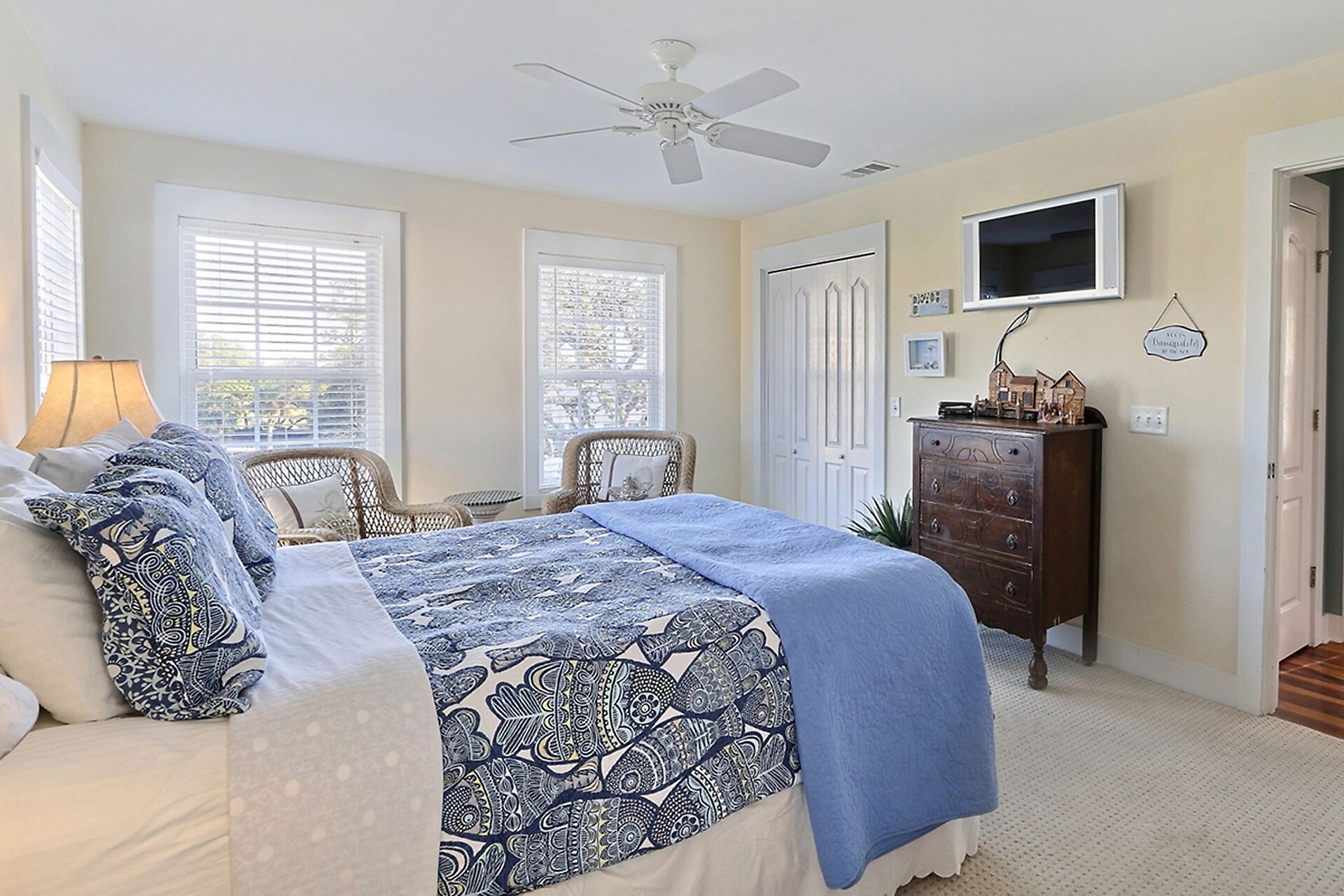 A bedroom with a bed, a dresser, a television, and a ceiling fan.