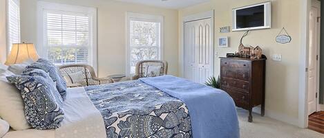 A bedroom with a bed, a dresser, a television, and a ceiling fan.