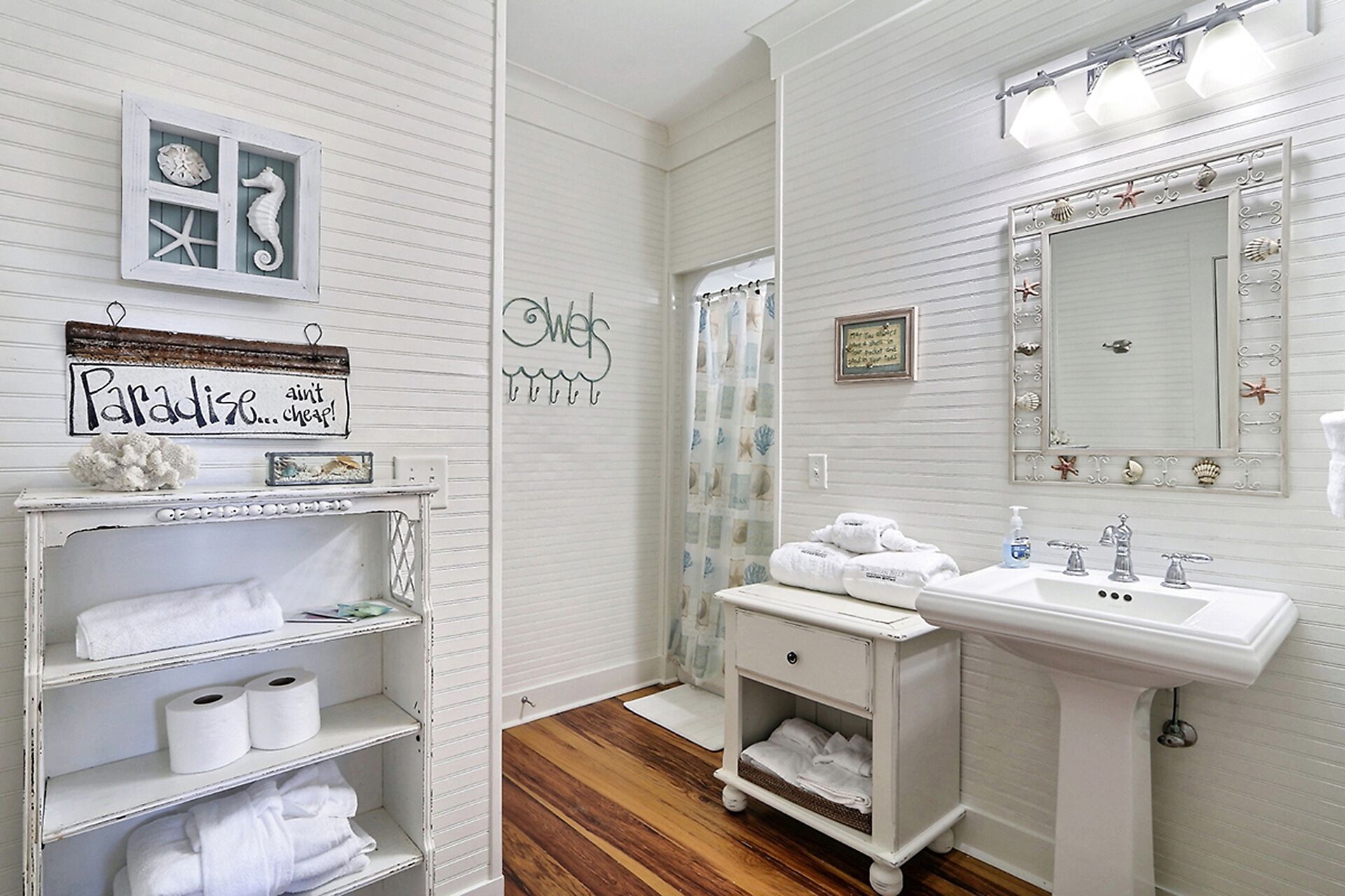 A bathroom with a vanity, a mirror with decorative elements, and a shelf with towels and toiletries.