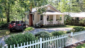 A house with a porch, a gravel driveway, and a white picket fence.
