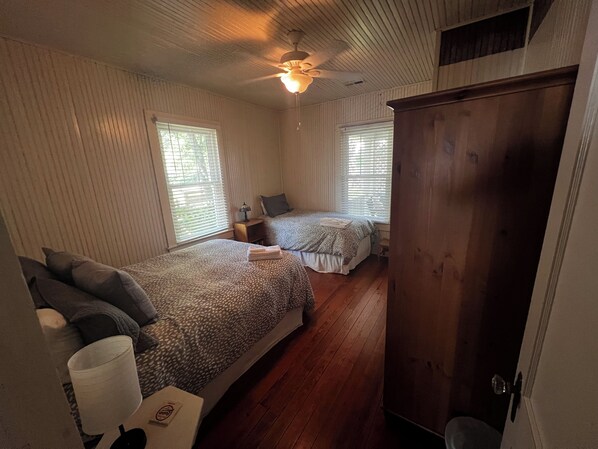 A room with two beds, wooden flooring, a ceiling fan, and a wooden wardrobe. - Brevard Bungalow
2 level, steps to Downtown, Music Center, Lumberyard, Greenway. (Brevard)