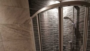 Un baño moderno con ducha de vidrio, lavamanos blanco y un inodoro.