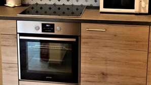 Una cocina con armarios de madera, un horno de acero inoxidable, un microondas y un salpicadero decorado.