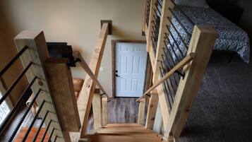 Staircase leads to a cozy bedroom with a patterned bedspread and a window.
