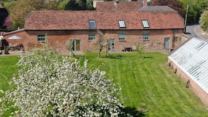 A brick building with a flat roof, multiple windows, and a well-maintained lawn. - Manor Farm Courtyard Cottages (Thatcham)