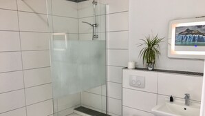 A modern bathroom with a glass-enclosed shower, a toilet, and a sink.