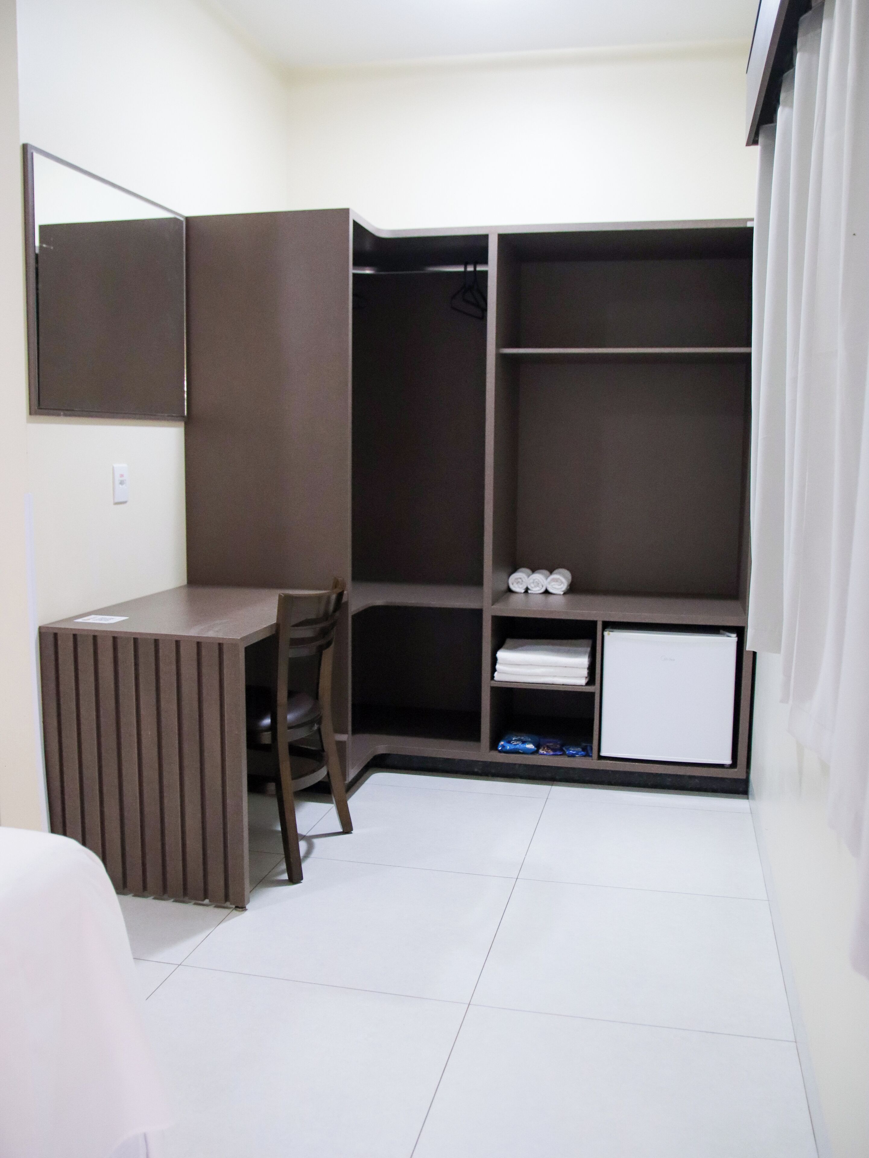 A compact bedroom with a bed, a desk, and a wardrobe.