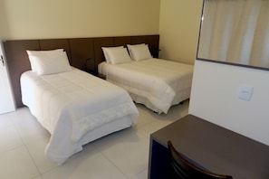Two single beds with matching headboards and white bedding, a small desk and chair for work or dining.