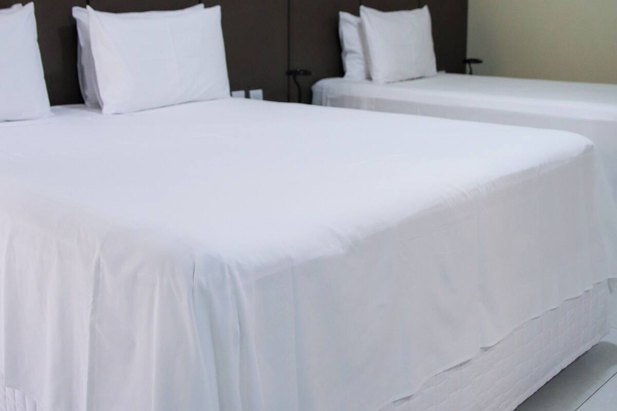 Two single beds with white linens in a hotel room.