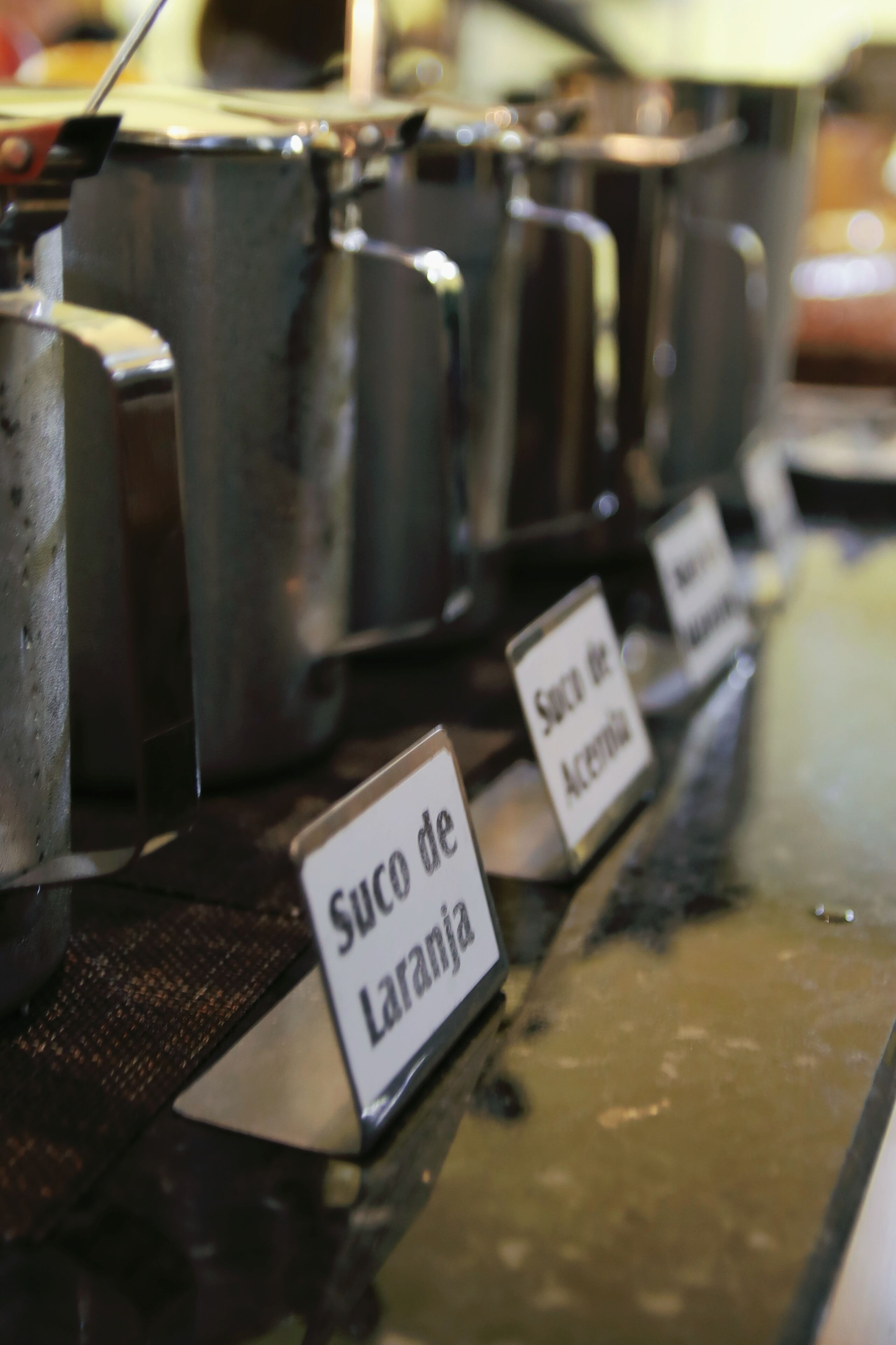A buffet area with labeled dishes, including 'Suco de Laranja'.