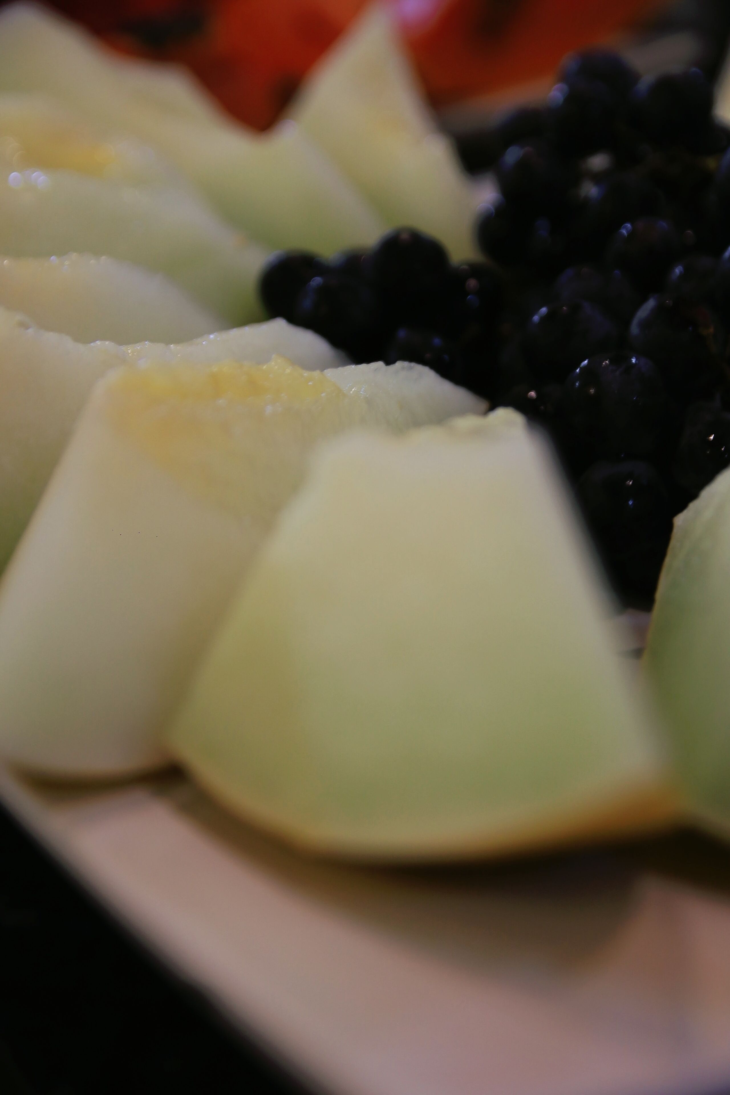 Et nærbillede af en frugtfat med melonstykker og brombær.