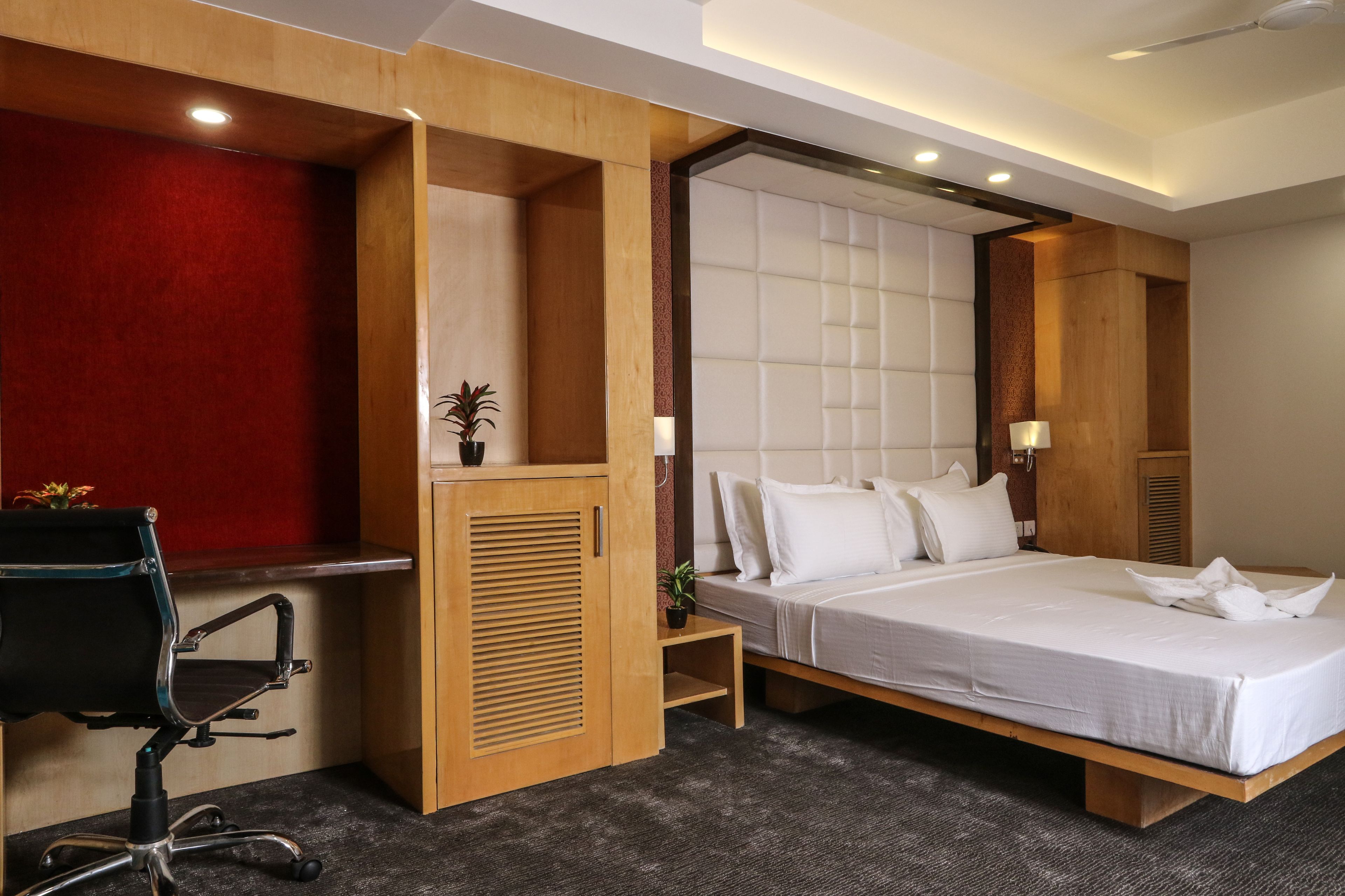 A modern hotel room with a large bed, a desk, and a chair.