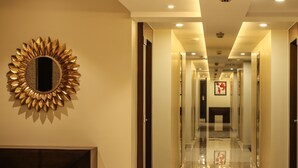 Un pasillo de hotel con un espejo de sol, un cuadro en la pared y un piso pulido.