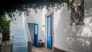 Un corridoio stretto con una scala che conduce a una stanza, una porta blu e un piatto decorativo appeso al muro.