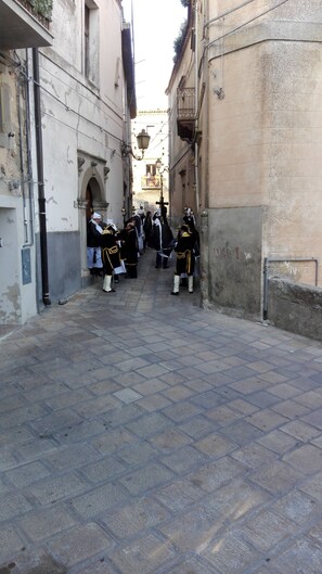 A narrow street with buildings on either side, featuring a cobblestone pavement and a few people in uniform. - San Procopio (Troina)