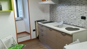 Una cocina compacta con armarios de madera, una encimera blanca y una ventana.