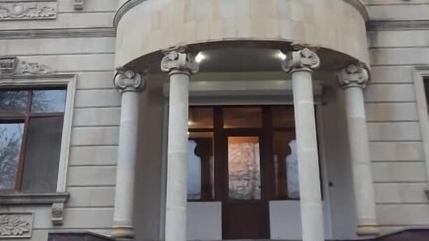 A building with a central entrance flanked by columns, a curved facade, and multiple windows. - Yeshim Guest House (Baku)