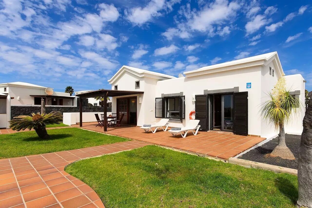 A modern house with a patio, outdoor seating, and a well-maintained lawn.