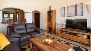 Una sala de estar moderna con un sofá de cuero, un mueble de entretenimiento de madera y un televisor de pantalla plana.
