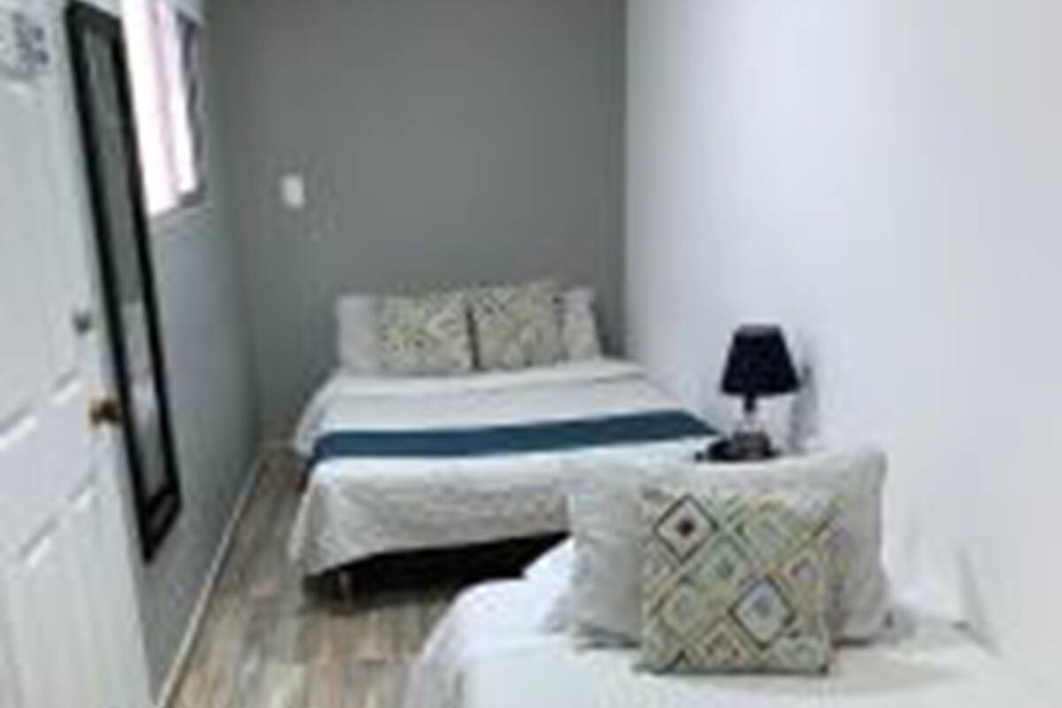 Une chambre avec deux lits, une table de chevet avec une lampe et une armoire.