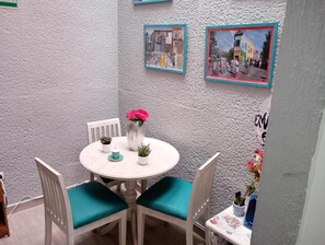 A small round table with chairs, a vase with flowers, and framed pictures on the wall. - Hotel Maceo 55 (Bogotá)