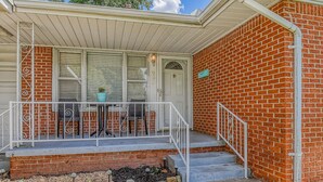 A residential house with a porch, a brick exterior, and a mailbox.