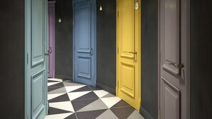 A hallway with three doors in different colors (blue, yellow, and grey) and a black and white checkered floor. - Central Hostel (Kharkiv)