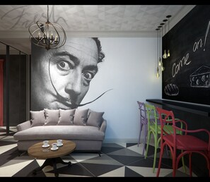 A modern living room with a large wall mural, a sofa, a coffee table, and colorful chairs. - Central Hostel (Kharkiv)