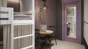 A room with a bunk bed, a desk with a laptop, a chair, and a door with a mirror. - Central Hostel (Kharkiv)