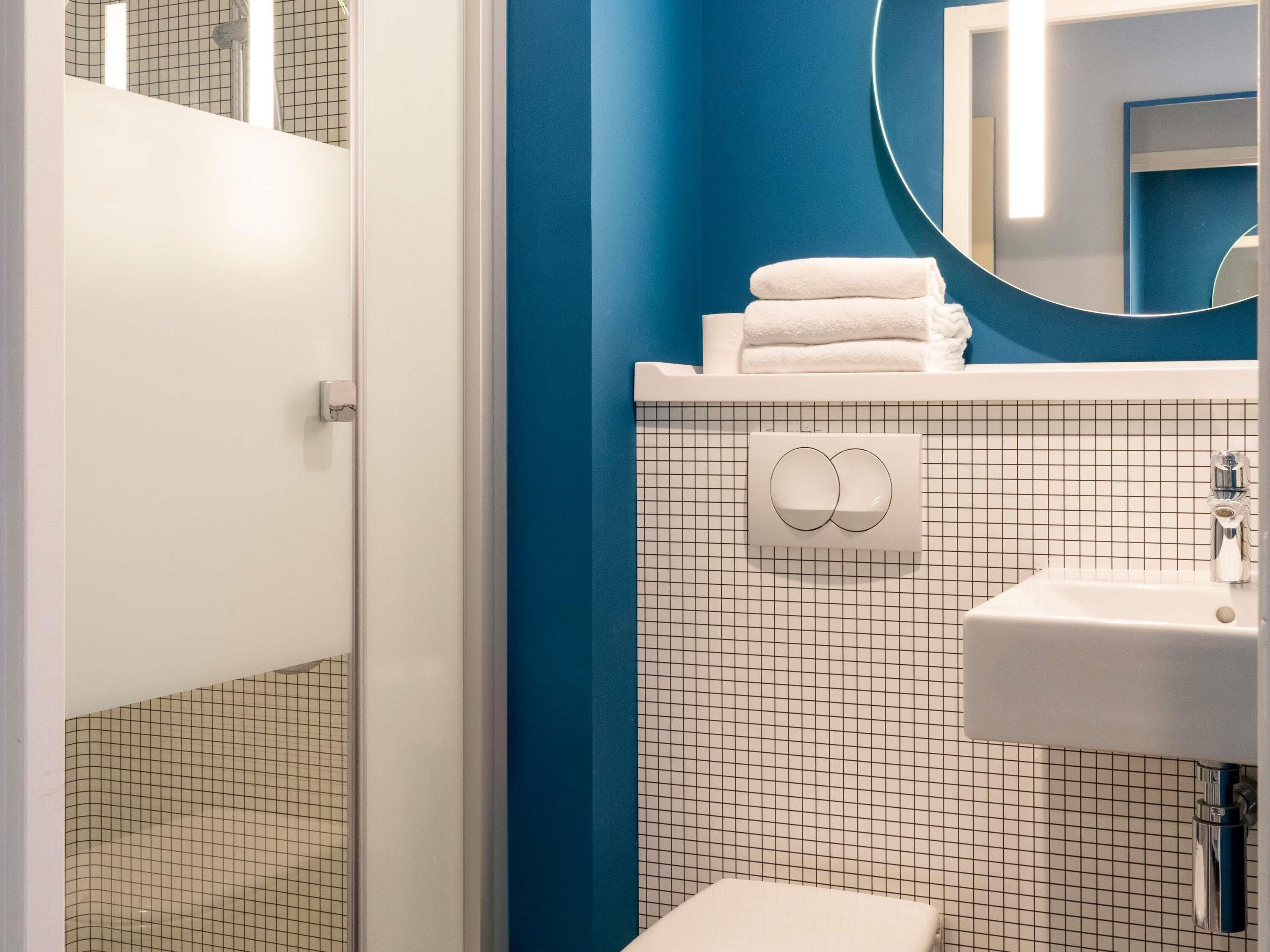 A bathroom with a white sink, a mirror, and a towel rack.