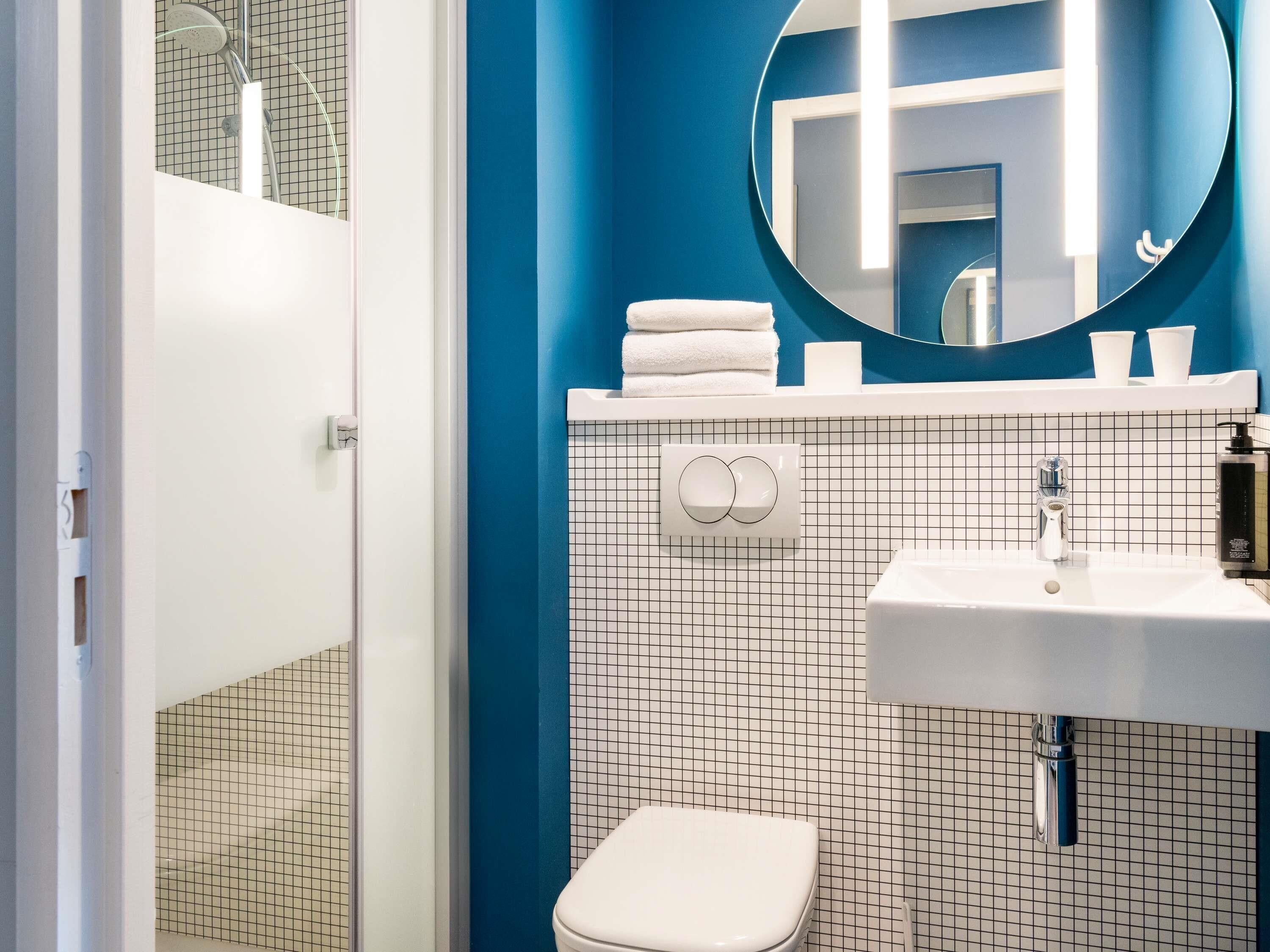 Een badkamer met een witte wastafel, toilet, spiegel en douche.