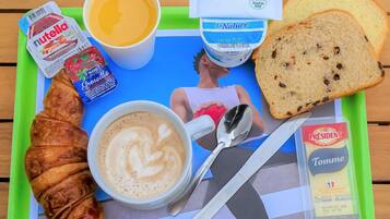 Un plateau avec un croissant, du Nutella, une tasse de café, une tranche de pain et un paquet de fromage Tomme.