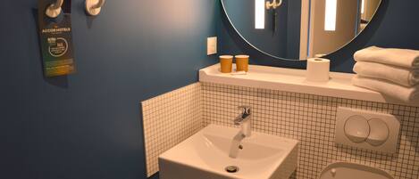 A bathroom with a white sink, a mirror, and a toilet. There are two towels stacked on the counter.