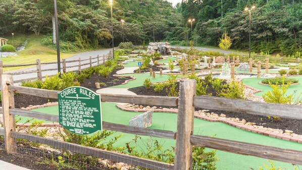 Un campo de mini golf con cerca de madera y un cartel que enumera las normas del juego.