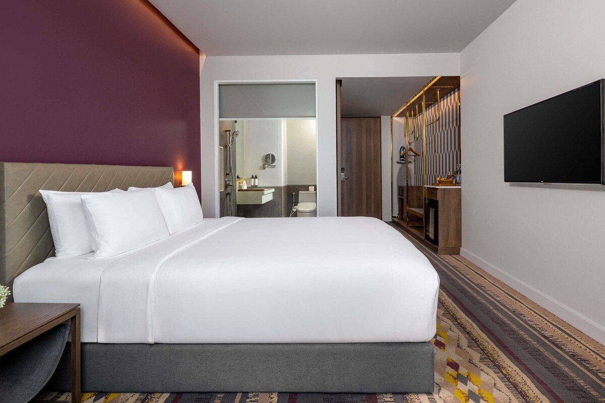 Ein Hotelzimmer mit Bett, Fernseher, Badezimmer und begehbarem Kleiderschrank.